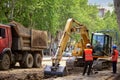 Public utility workers are replacing the water supply and sewerage system in the city. Working excavator on the roadway street Royalty Free Stock Photo