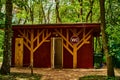 Public wooden toilet in the park. Summer house for a toilet among the trees on a sunny day. Pine forest for walks in Royalty Free Stock Photo