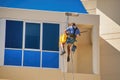 Public worker cleaning windows on the top of a tall building