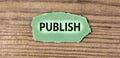 PUBLISH - word on green torn piece of paper on old brown board background