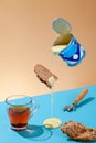 Puddle of condensed milk flows from levitating jar, can opener, black bread, glass of black tea Royalty Free Stock Photo