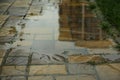 Puddle after rain on street tiles outdoors, closeup