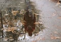 puddle with reflection of girl walking with backpack