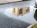 Puddle with reflection of municipal urban house Royalty Free Stock Photo