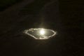 A puddle with the reflection of the sun in the form of an eye. Forest road in puddles after rain Royalty Free Stock Photo