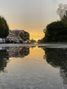 Puddle reflections in the urban road after rain at sunset golden hour. Cars and lights reflects Royalty Free Stock Photo