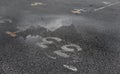 Puddle of water on asphalt road reflecting the sky.