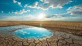 Puddle of water in parched field with cracked soil. Drought, climate change, fresh water shortage and fertile land Royalty Free Stock Photo