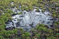 A muddy puddle of water on a grass football pitch