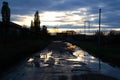 Puddles on a broken rural road at sunset. Royalty Free Stock Photo