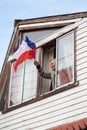 Mature woman with Chilean flag standing in windows. Chilean people in a massive protest at Puerto Montt. Social crisis