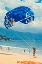 Man standing on the beach attached to the big blue parachute. Royalty Free Stock Photo