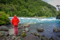 PUERTO VARAS, CHILE, SEPTEMBER, 23, 2018: Single tourist man wearing red jacket and enjoying the river in Saltos de