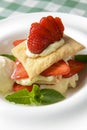 Puff pastries with strawberries and berry sauce on a white plate. Over green plaid background. Royalty Free Stock Photo