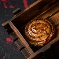 Puff pastry cinnamon bun. Fresh baked dough on wooden tray. Sweets and dessert. Square format. Soft focus