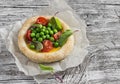 Puff pastry egg tartlet with fresh green peas and cherry tomatoes on wooden rustic board.