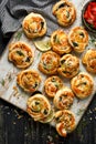 Puff Pastry Pinwheels stuffed with salmon, cheese and spinach served on a board on a black wooden table