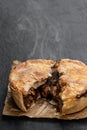 Puff pastry steak pie on baking paper on black stone background