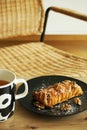 Puff pastry with walnuts and powdered sugar on a black plate next to a cup of tea Royalty Free Stock Photo