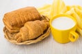 Puff pastry in wicker basket, yellow napkin, milk in cup