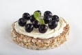 Puffed exploded wheat grains with blueberries on a thin layer of soft cheese on a light wooden background.