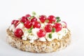 Puffed exploded wheat grains with curd cheese, red currants and microgreens on a light wooden background.