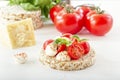 Puffed exploded wheat grains with slices of mozzarella and chili tomato sprinkled with pepper on a light wooden table