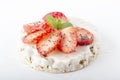 Puffed exploded wheat grains with white chocolate frosting with chopped strawberries, chia seeds and mint leaves on a light wooden