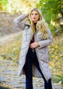 Puffer fashion trend concept. Girl fashionable blonde walk in autumn park. Woman wear warm grey jacket. Jacket everyone