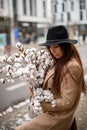 Puffy white bouquet in hands of a woman in a beige jacket and a elegant black hat Royalty Free Stock Photo