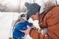 Pug dog walking on snow with his master. Puppy wearing winter coat. Man hugging his pet in winter forest Royalty Free Stock Photo