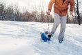 Pug dog walking on snow with man. Puppy wearing winter coat outdoors Royalty Free Stock Photo