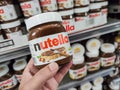 Closeup of Man hand buying Nutella jar of hazelnut cream in french supermaket shelf