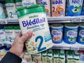 A consumer chooses a box of Bledilait brand baby milk from the baby food section of a supermarket