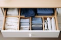 a pull-out shelf in a chest of drawers with things arranged in an organized and neat manner