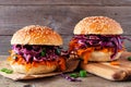 Healthy, plant based meatless pulled carrot burgers against a dark wood background