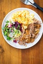 Pulled pork with mashed potatoes and mixed leaves salad on white plate