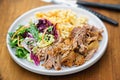 Pulled pork with mashed potatoes and mixed leaves salad on white plate