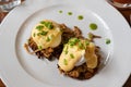 Pulled pork served on fried potato pancakes topped with poached egg and garnished with hollandaise sauce and fresh green onion aka Royalty Free Stock Photo