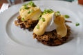 Pulled pork served on fried potato pancakes topped with poached egg and garnished with hollandaise sauce and fresh green onion aka Royalty Free Stock Photo