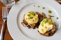 Pulled pork served on fried potato pancakes topped with poached egg and garnished with hollandaise sauce and fresh green onion aka Royalty Free Stock Photo