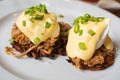 Pulled pork served on fried potato pancakes topped with poached egg and garnished with hollandaise sauce and fresh green onion aka Royalty Free Stock Photo