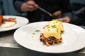 Pulled pork served on fried potato pancakes topped with poached egg and garnished with hollandaise sauce and fresh green onion aka Royalty Free Stock Photo