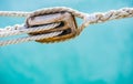 Yachting, detail view of wooden sailboat pulley with ropes and sea water background Royalty Free Stock Photo