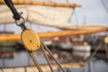 Pulley for sails and ropes made from wood on an old sail boat, with sail and other boats out of focus in the background. Royalty Free Stock Photo