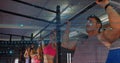 Pulling adults on rig, man in grey tank doing pull-up at gym, blue overlay, copy space Royalty Free Stock Photo
