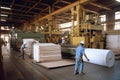 pulp and paper processing plant, with workers loading carts with freshly made sheets of paper