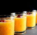 Pulpy orange drink with cherry in shot glasses