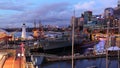 Pulsating city at harbor with navy ship by dusk
