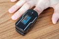 Pulse oximeter on the index finger on a wooden background. Measurement of blood oxygen and pulse. Close-up Royalty Free Stock Photo